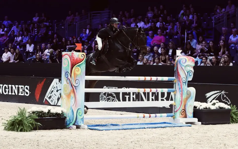Cavalière du club en concours de saut d'obstacles sur une piste couverte